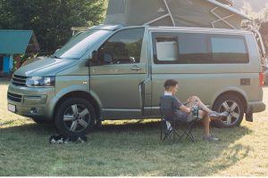 Campervan with pet dog on camping site.